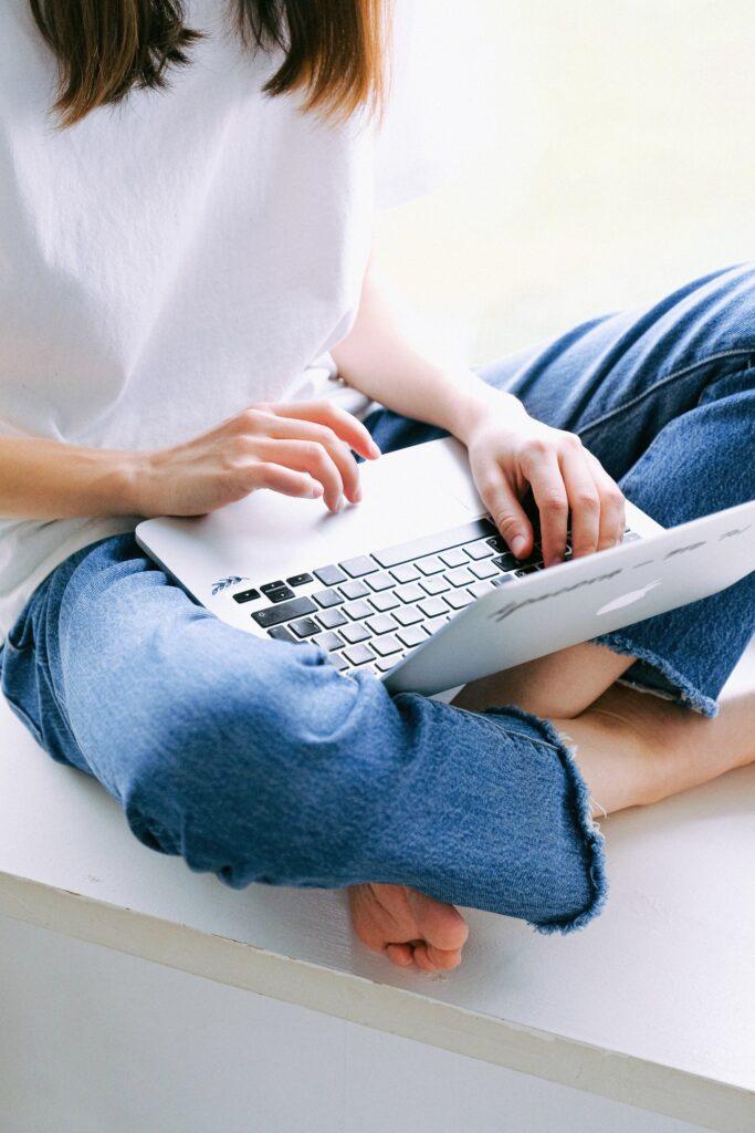 Frau sitzt überkreuz mit Laptop auf dem Schoß