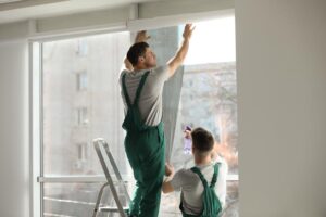Professionelle Arbeiter tönen Fenster mit Folie im Innenbereich